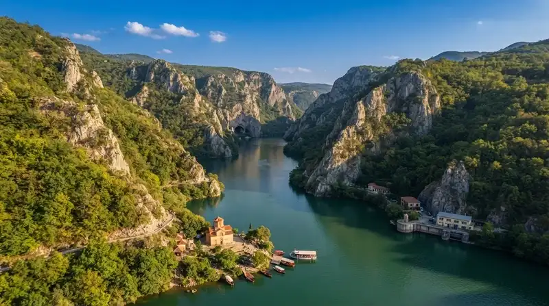 Kanjon sa smaragdnozelenom rekom, strmim stenovitim liticama, manastirom na obali i privezanim čamcima